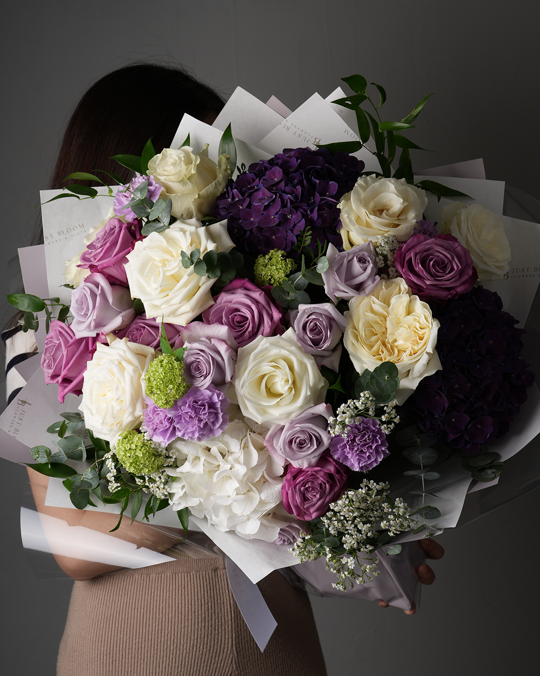 Emersyn bouquet with purple and cream roses, hydrangeas, and carnations in full view.