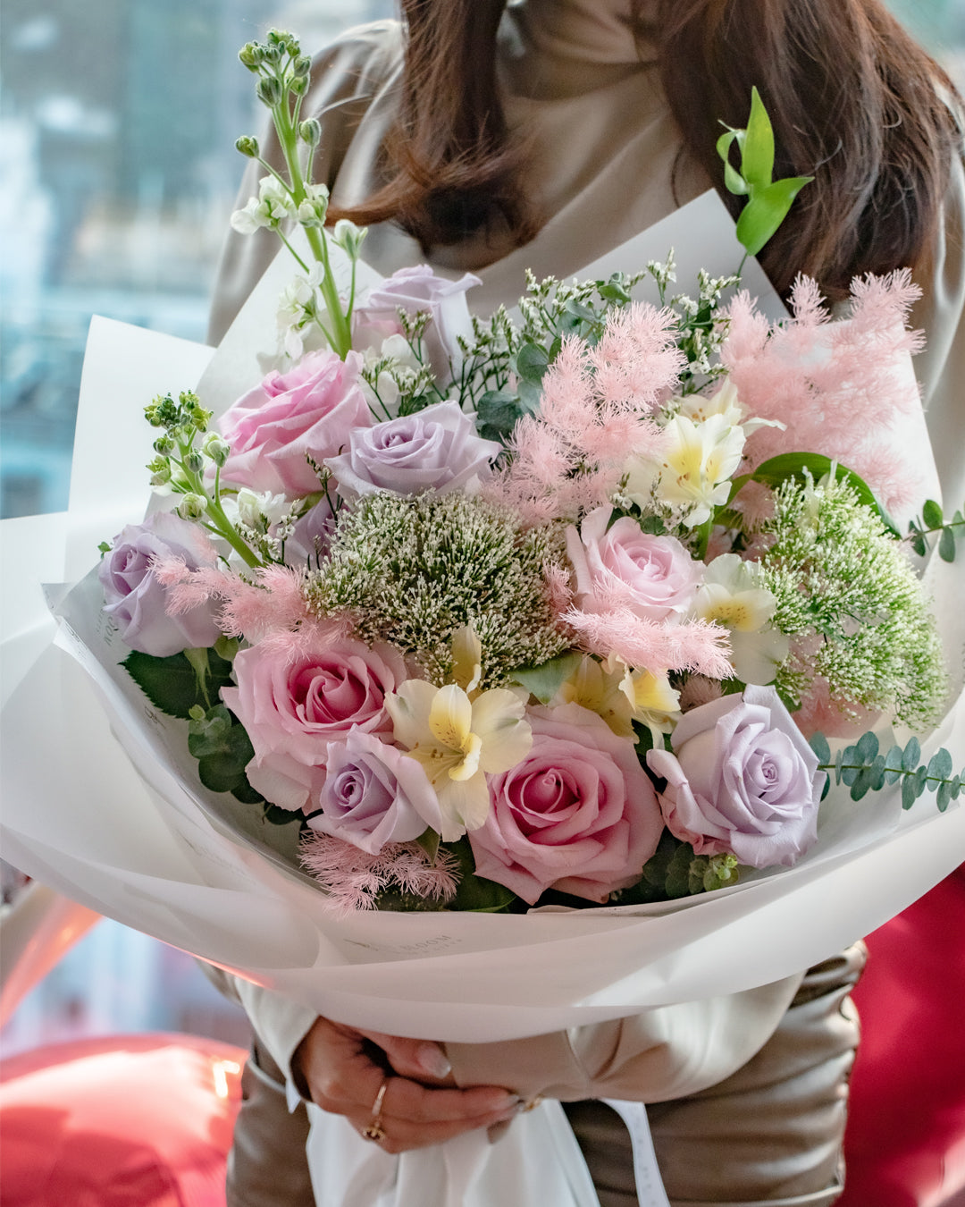 Woman holding Kisses pink rose bouquet with smoke grass in natural lighting