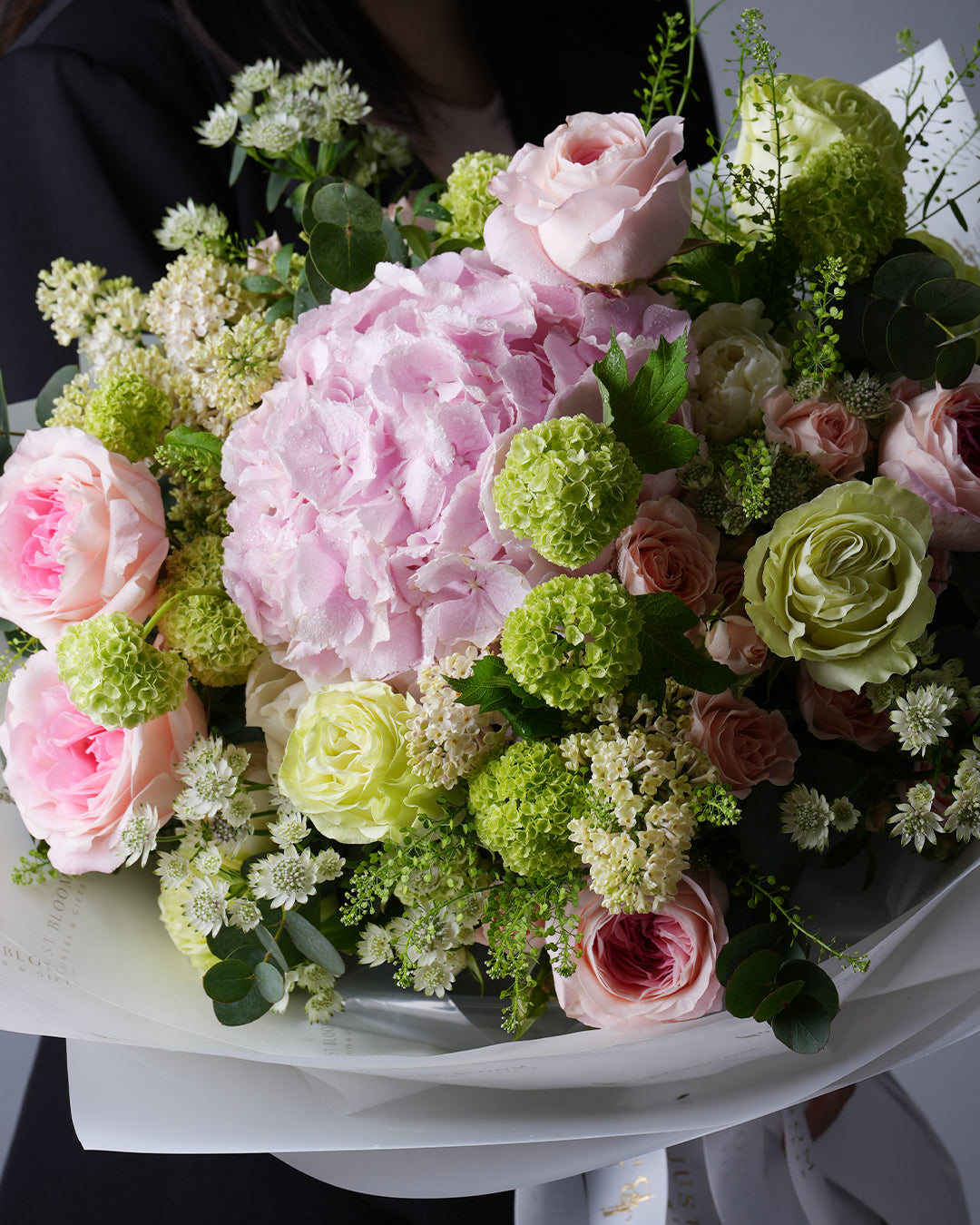 Close-up view of Leilani bouquet showing pink hydrangeas, green roses, and white filler flowers