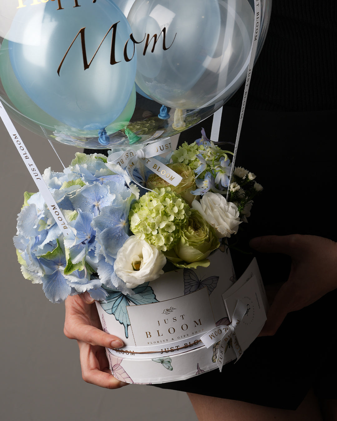 Close-up of Madeline flower box showing hydrangeas, roses, viburnums, and delphiniums in butterfly-print hatbox