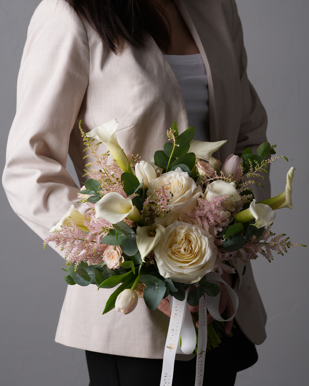 Maria elegant white and blush bridal bouquet with roses, calla lilies, tulips, and astilbes – held by bride