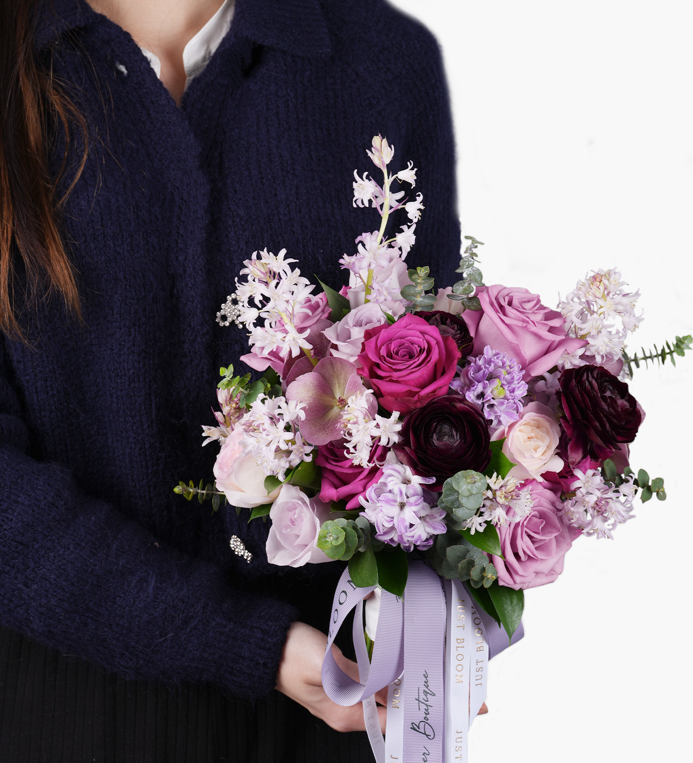 Nina bouquet held by model featuring purple roses and romantic plum-toned florals